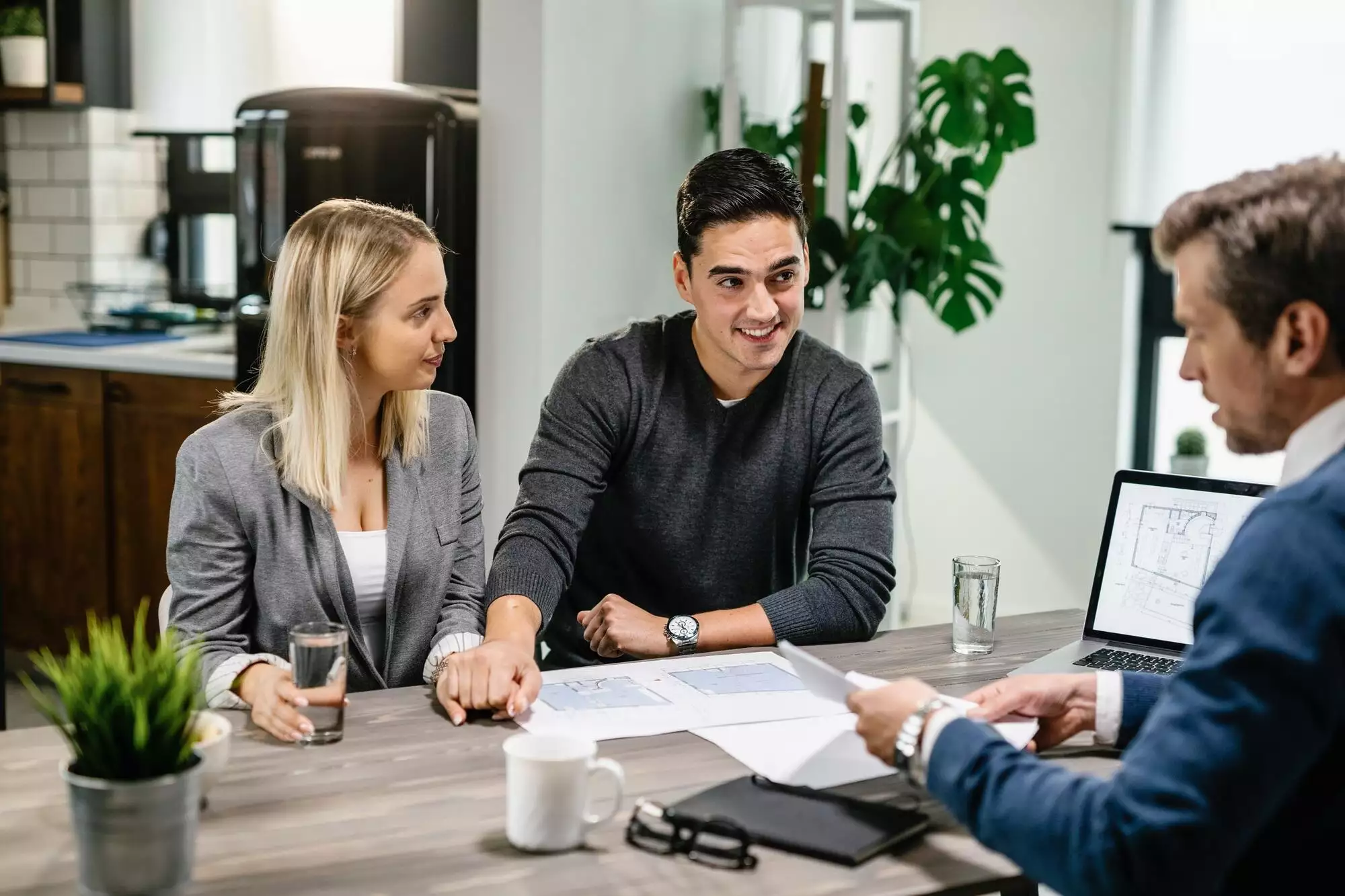 Young happy couple having consultations with real estate agent at home.